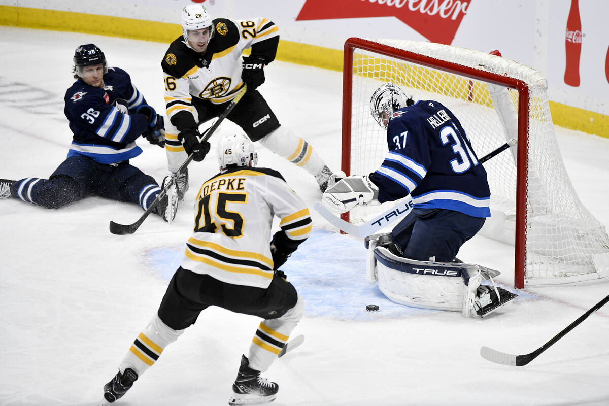 Winnipeg Jets goaltender Connor Hellebuyck makes a save on a Boston Bruins shot as Bruins' Marc ...