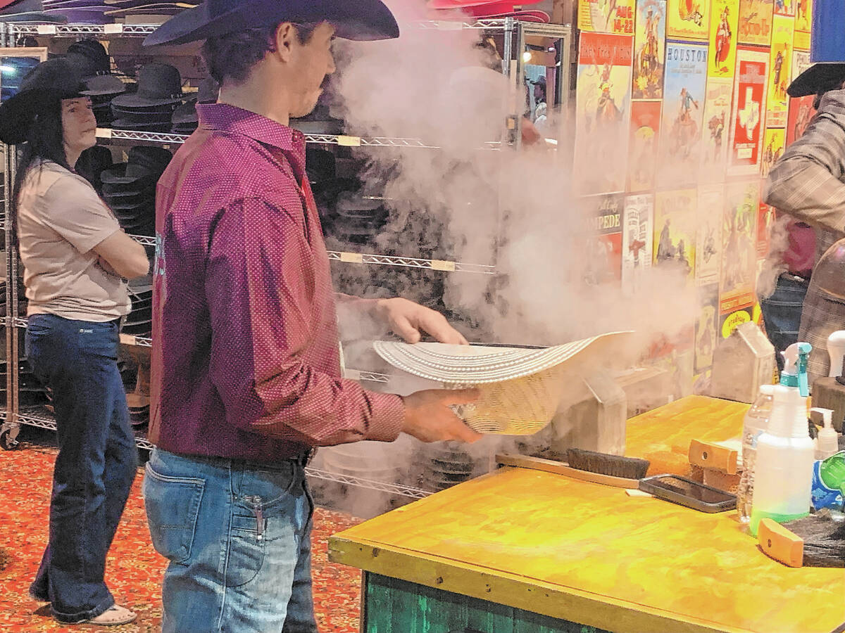 Joe Young steams and shapes a new cowboy hat for a customer at the Heads or Tails Hats booth Tu ...