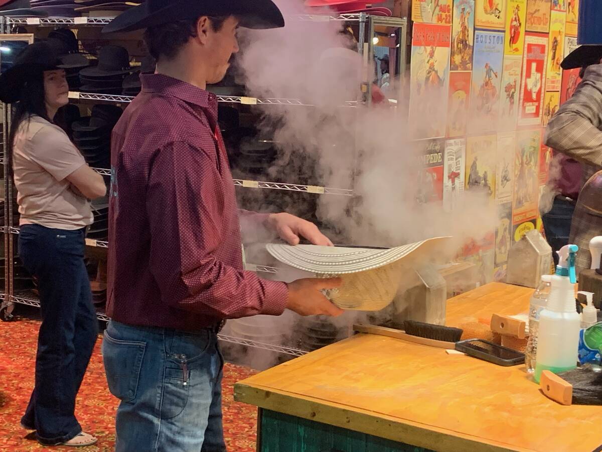 Joe Young steams and shapes a new cowboy hat for a customer at the Heads or Tails Hats booth Tu ...