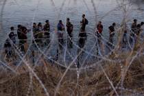 FILE - Migrants wait to climb over concertina wire after they crossed the Rio Grande and entere ...