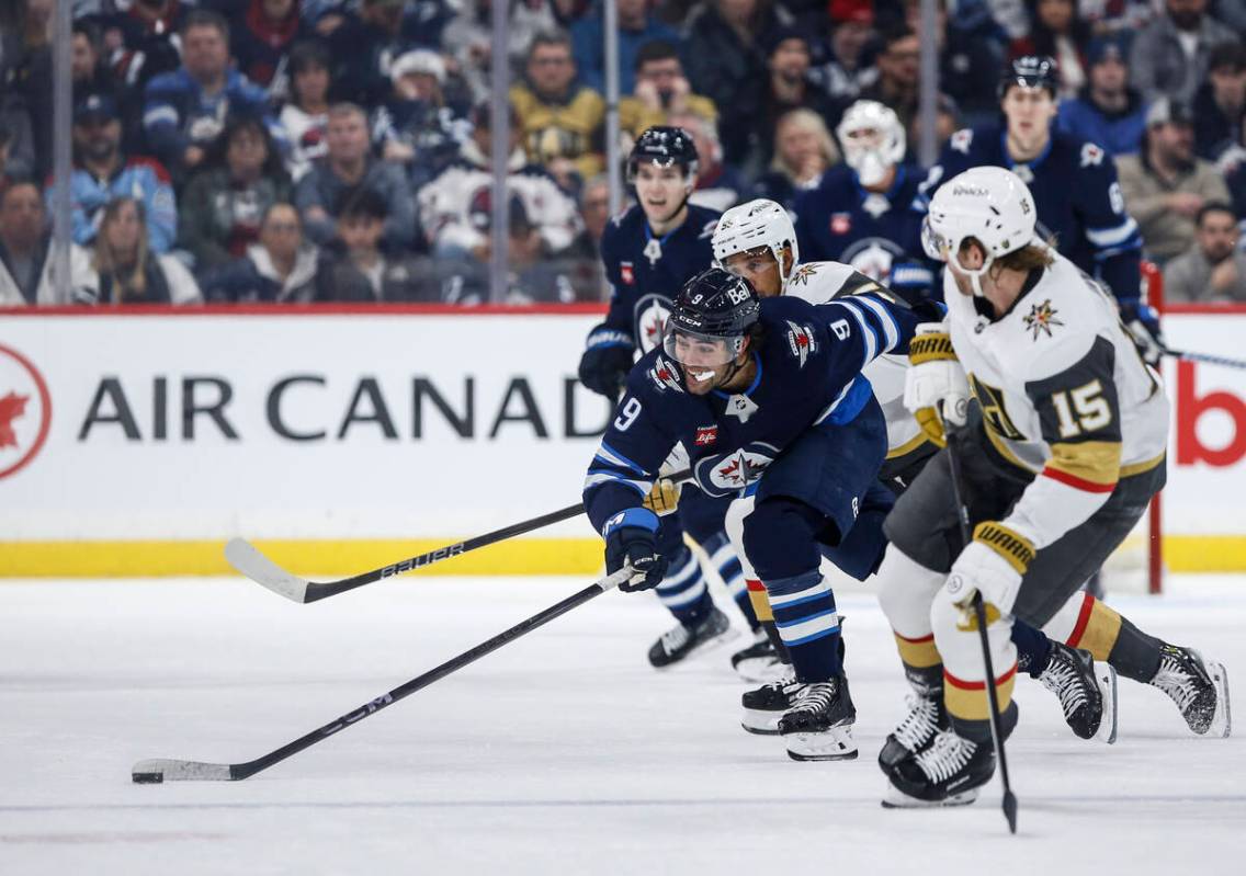 Winnipeg Jets' Alex Iafallo (9) chases down a loose puck as Vegas Golden Knights' Noah Hanifin ...