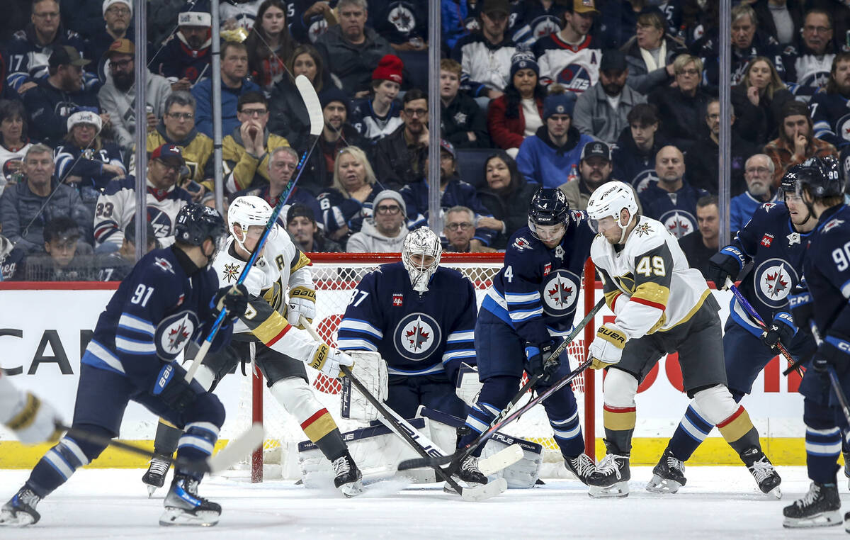 Winnipeg Jets goaltender Connor Hellebuyck (37) watches a shot by the Vegas Golden Knights duri ...