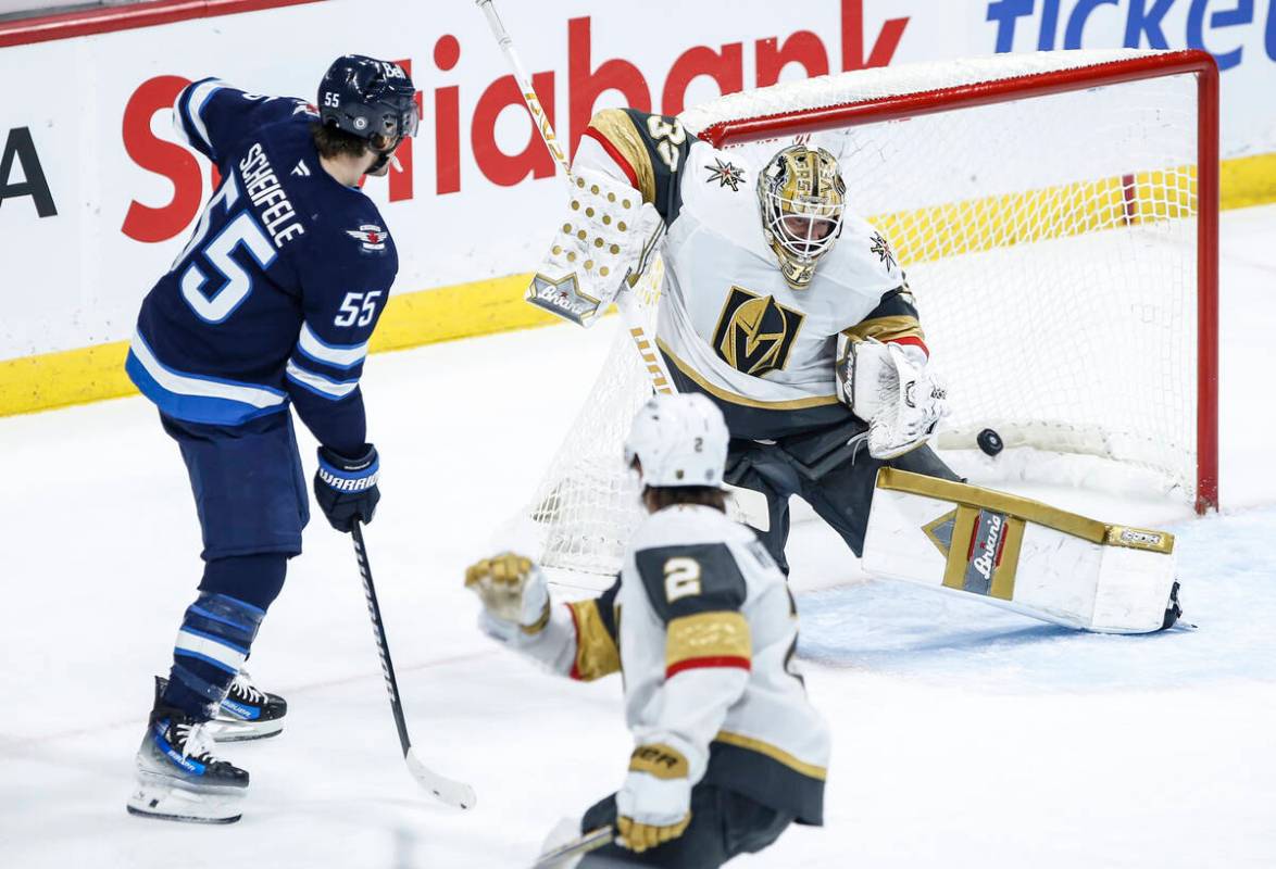 Winnipeg Jets' Mark Scheifele (55) looks on as Josh Morrissey's (44) shot gets past Vegas Golde ...