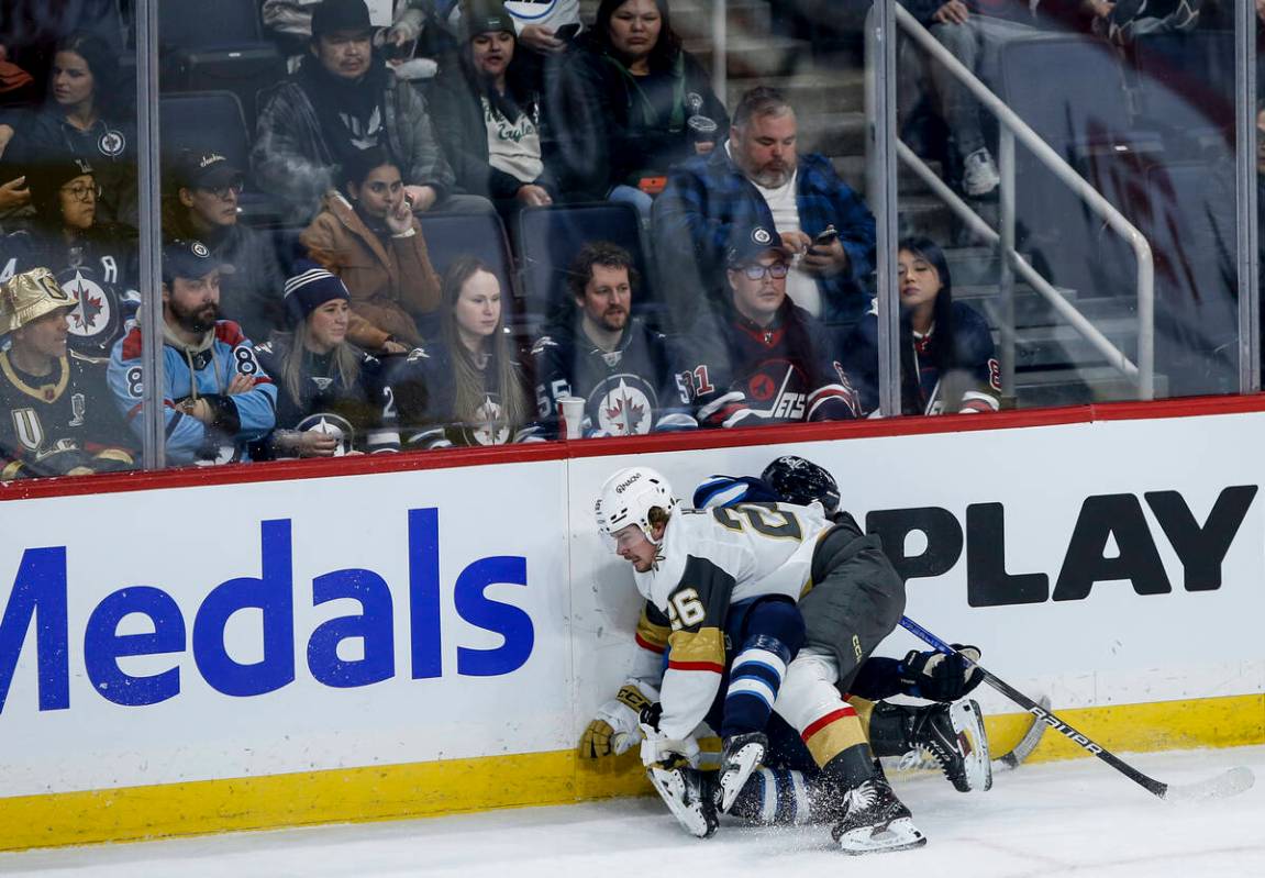 Vegas Golden Knights' Alexander Holtz (26) collides with Winnipeg Jets' Ville Heinola (14) duri ...