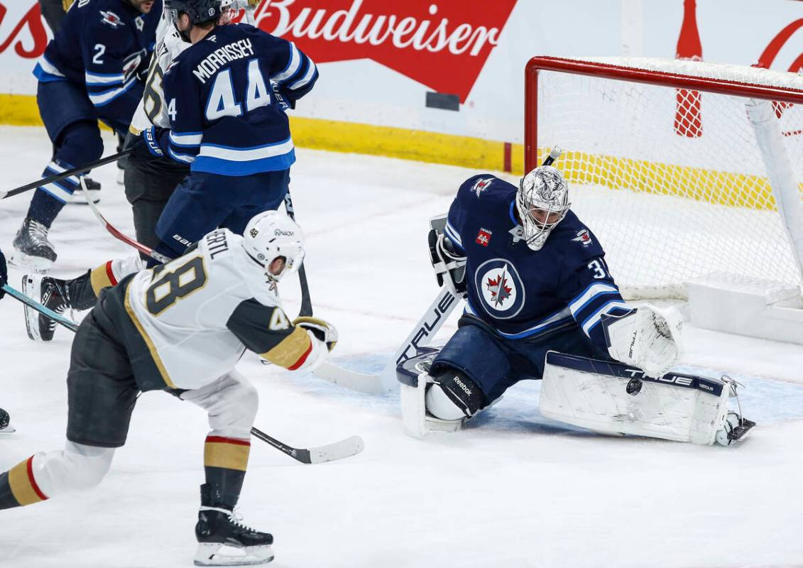 Winnipeg Jets goaltender Connor Hellebuyck (37) stops a backhander by Vegas Golden Knights' Tom ...