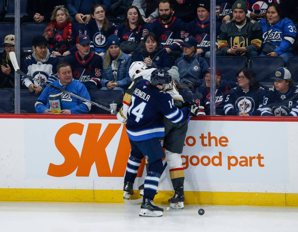 Winnipeg Jets' Ville Heinola (14) collides with Vegas Golden Knights' Nicolas Roy, back, during ...