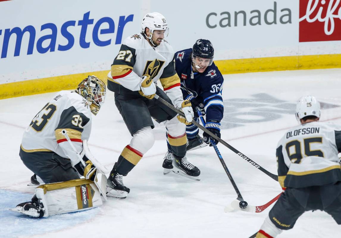 Vegas Golden Knights' Shea Theodore (27) defends against Winnipeg Jets' Morgan Barron (36) who ...