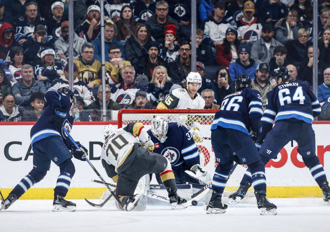 Winnipeg Jets goaltender Connor Hellebuyck (37) saves a shot by Vegas Golden Knights' Tanner Pe ...