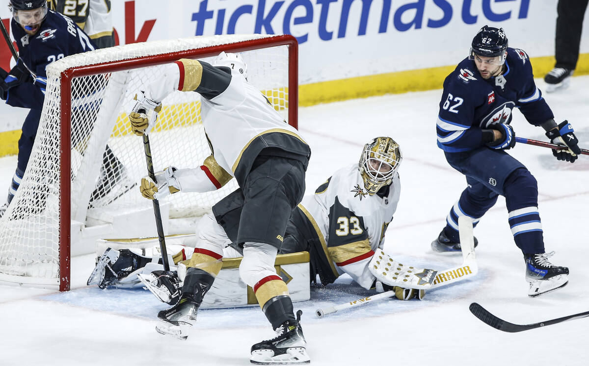 Vegas Golden Knights Alex Pietrangelo (7) covers the puck for goaltender Adin Hill (33) as Winn ...