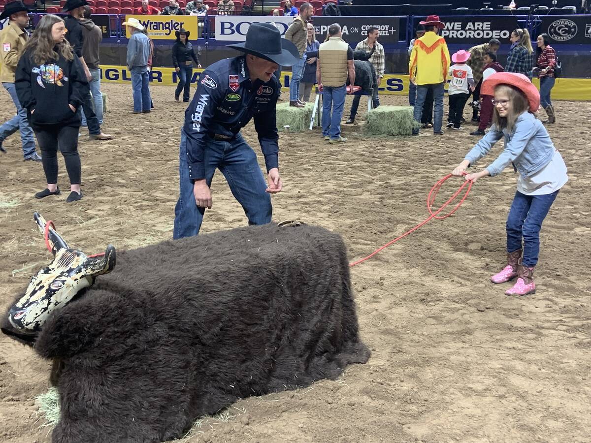 Wrangler NFR bullfighter Cody Webster helps Addysen Agasi, 11, rope a plastic practice steer du ...