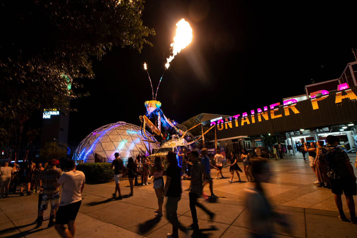 Attendees walk by the pyrotechnic praying mantis at the Container Park during the first day of ...