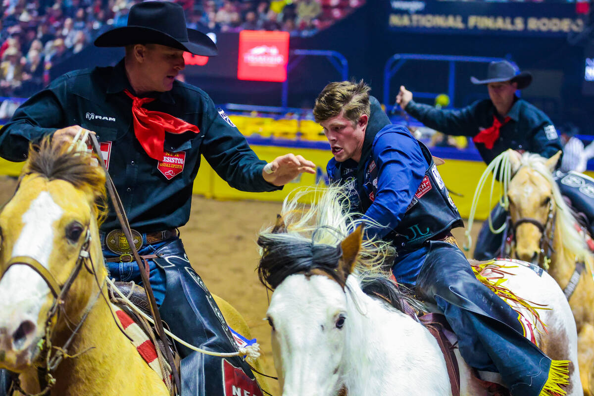 Bareback rider Jacob Lees gets help after his ride from the pick-up men during the final night ...