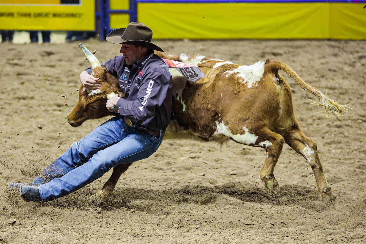 Steer wrestler Scott Guenthner slides into the dirt to wrestle the steer during the final night ...