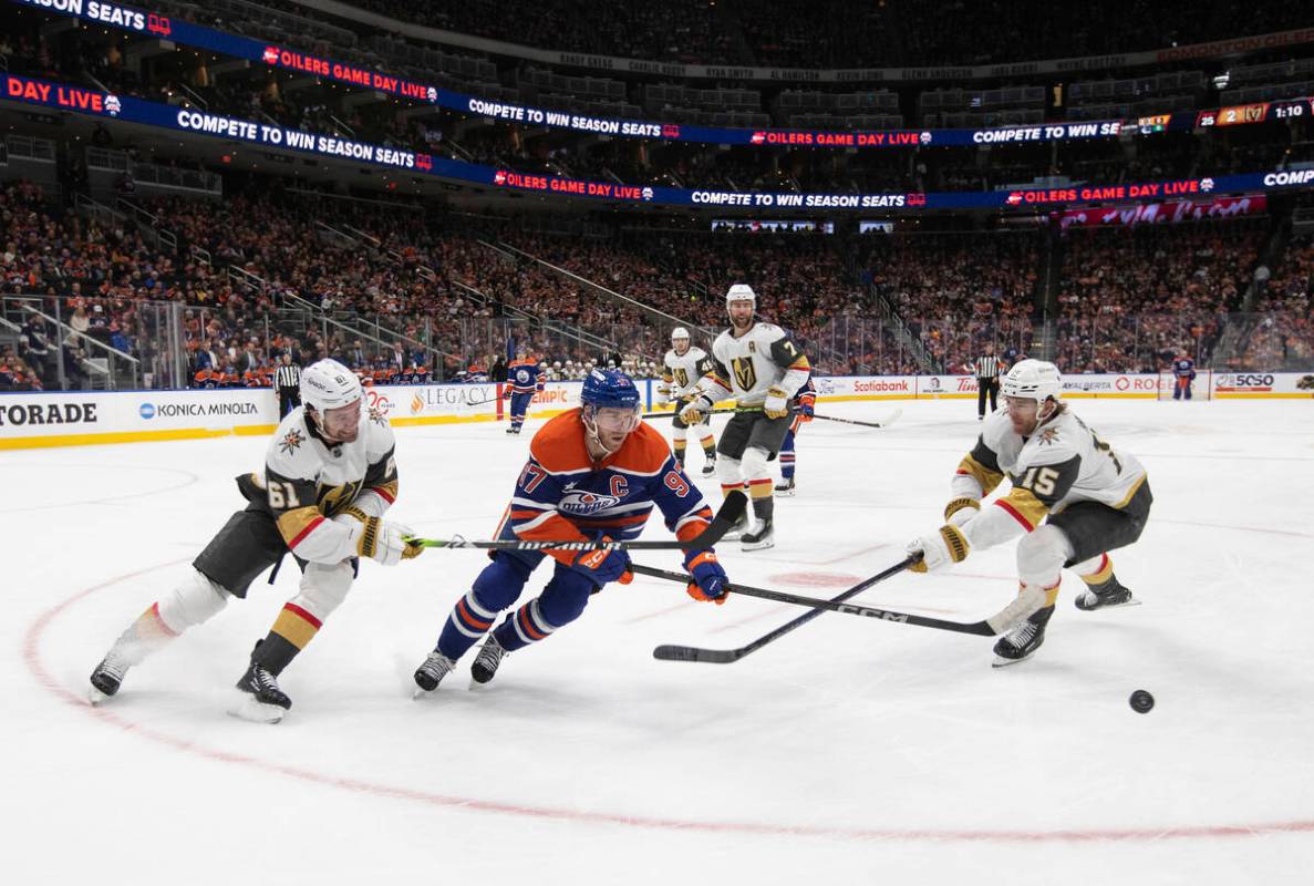 Vegas Golden Knights' Mark Stone (61) and Noah Hanifin (15) battle for the puck with Edmonton O ...