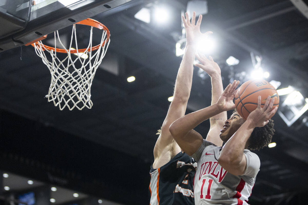 UNLV guard Dedan Thomas Jr. (11) attempts a shot around Pacific Tigers forward Elias Ralph (2) ...