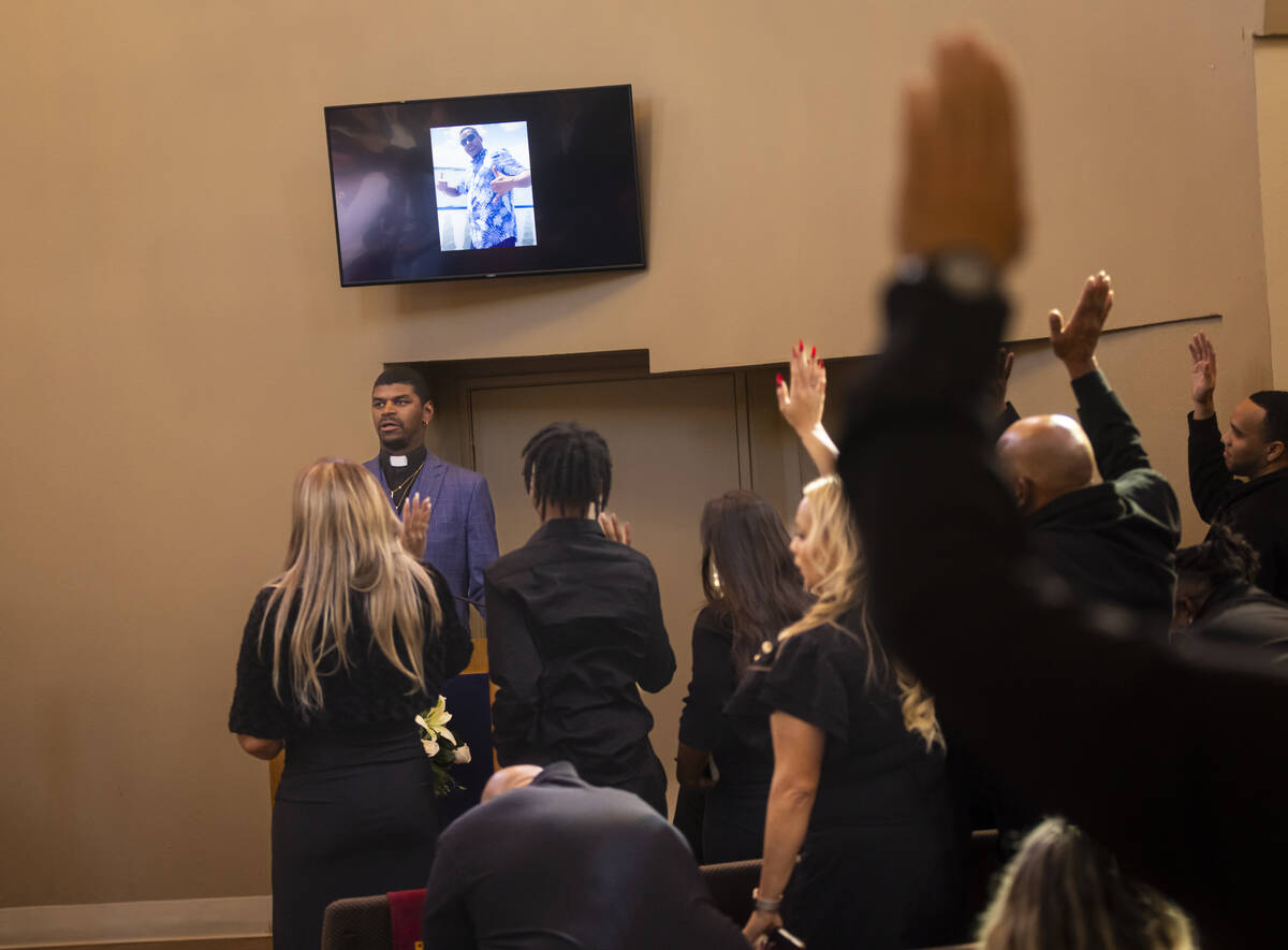 People raise their hands in response to a question during the funeral service for Brandon Durha ...