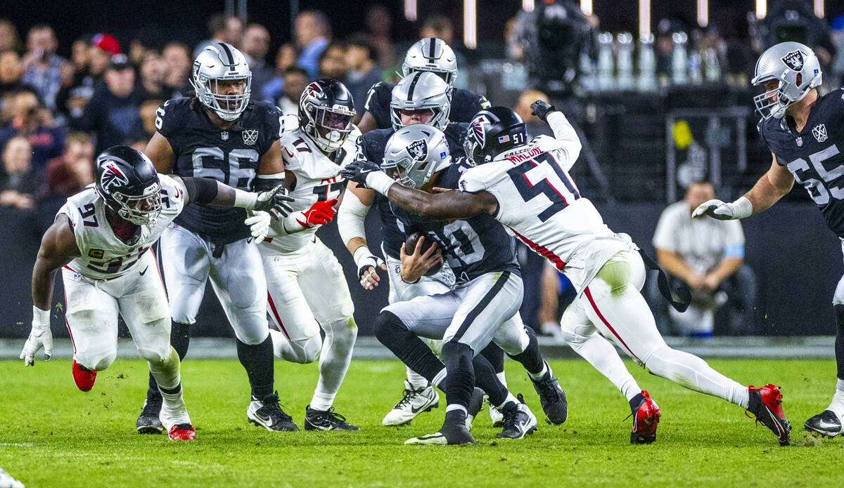 Raiders quarterback Desmond Ridder (10) battles for yards on a run as Atlanta Falcons linebacke ...