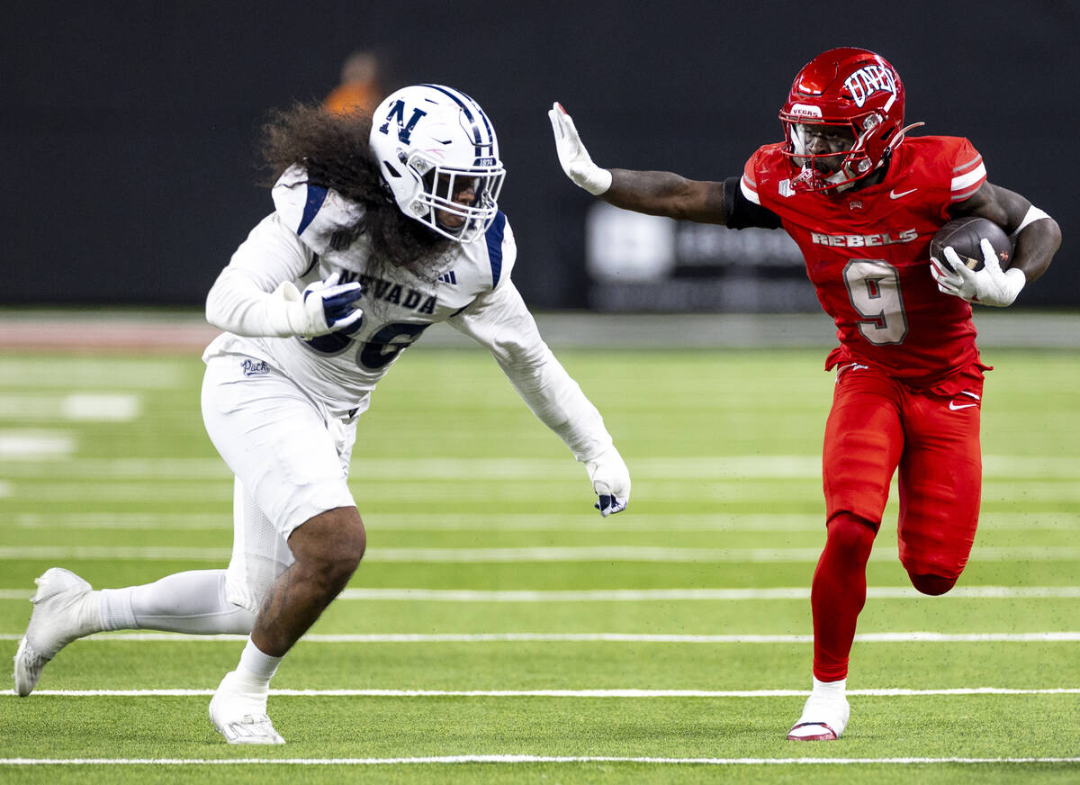 UNLV running back Jai'Den Thomas (9) looks to stiff arm UNR linebacker Tongiaki Mateialona, lef ...