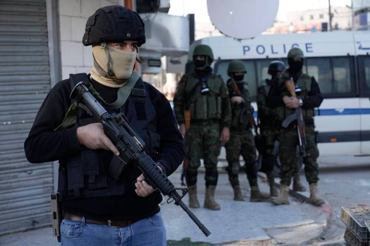 A officer from the Palestinian Authority clutches his gun as Palestinian security forces mount ...