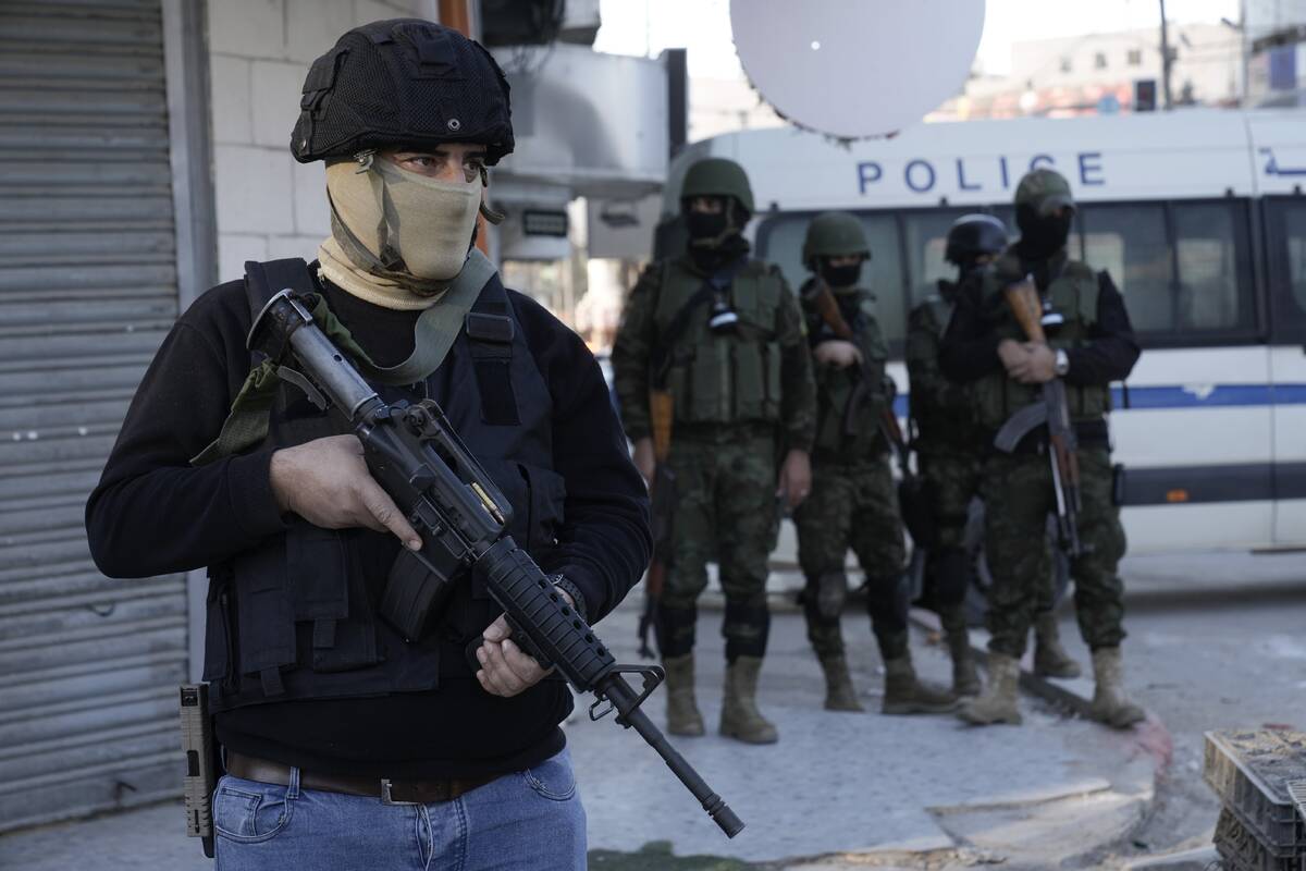 A officer from the Palestinian Authority clutches his gun as Palestinian security forces mount ...