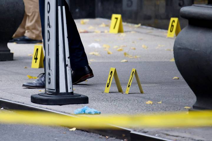 Members of the New York police crime scene unit investigate bullets lying on the sidewalk at th ...