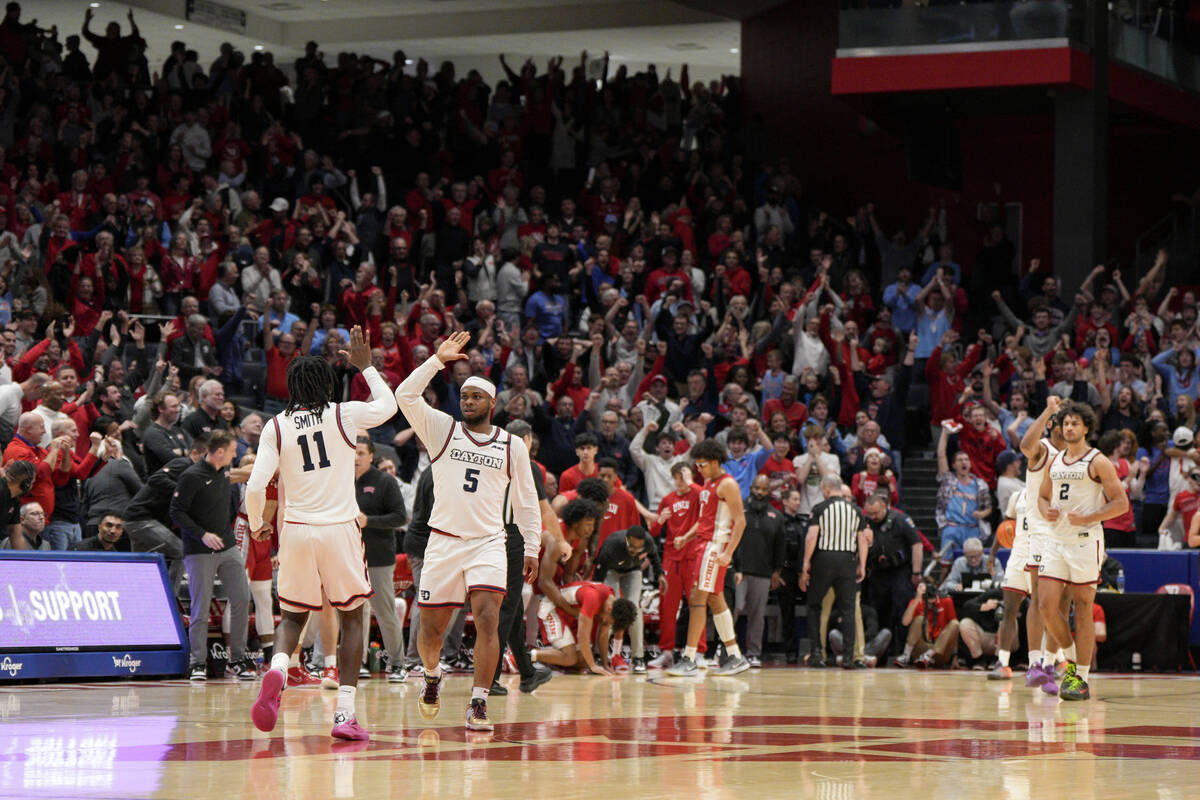 Dayton's Malachi Smith (11) celebrates with teammate Posh Alexander (5) following the team's 66 ...