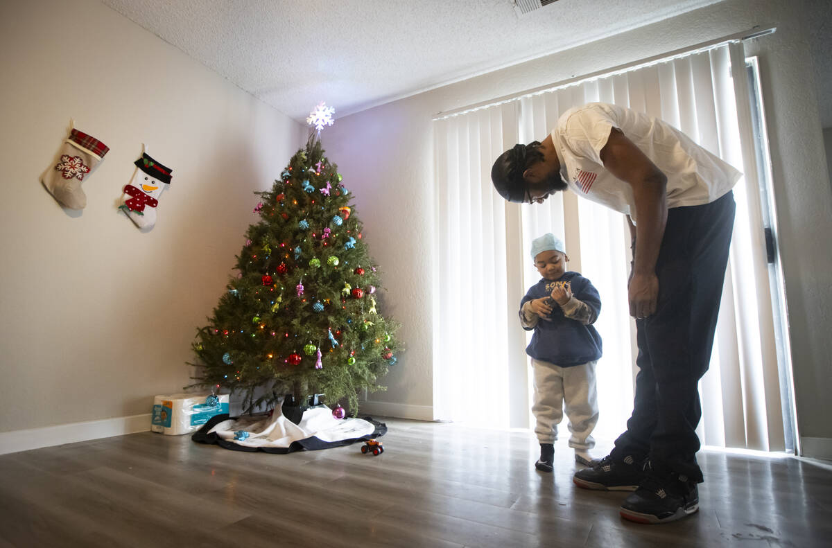 Angelo Crews, right, talks with his son Carmelo Crews, 3, as he plays with a toy that was donat ...