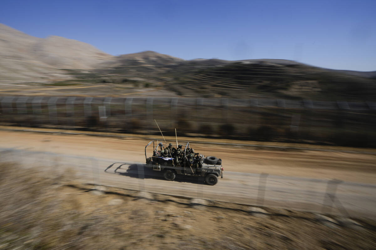 Israeli soldiers stand on an armoured vehicle after crossing the security fence along the so-ca ...