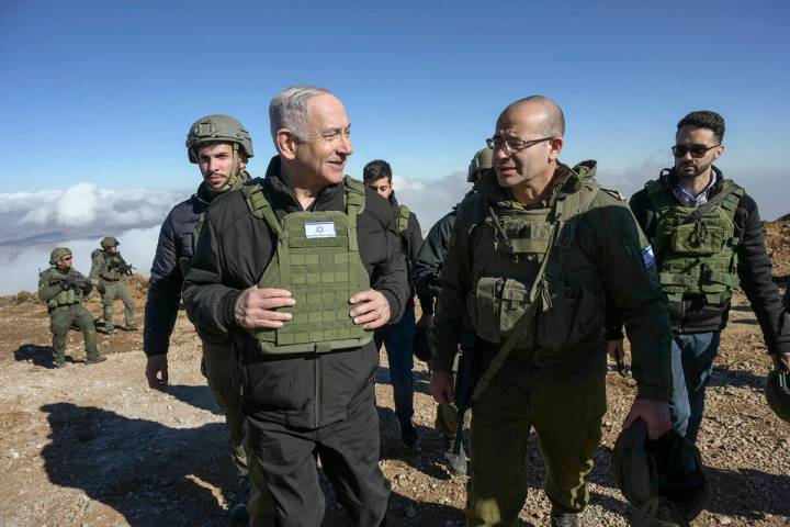 Israel's Prime Minister Benjamin Netanyahu, left, visits Israeli forces in a buffer zone inside ...