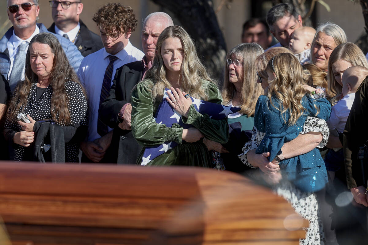 Ashlee Pulsipher, widow of Las Vegas police officer Colton Pulsipher, center, hugs the flag dur ...