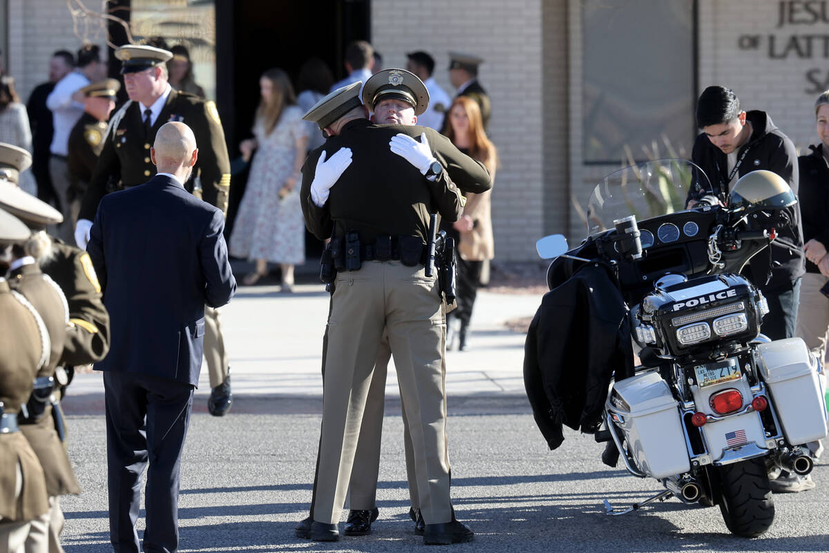 Officers comfort each other at the motorcycle of Las Vegas police officer Colton Pulsipher duri ...