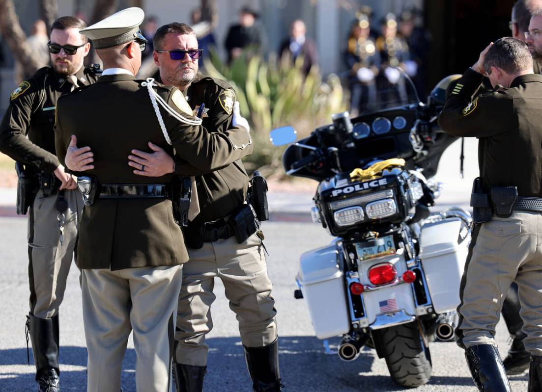 Officers comfort each other at the motorcycle of Las Vegas police officer Colton Pulsipher duri ...