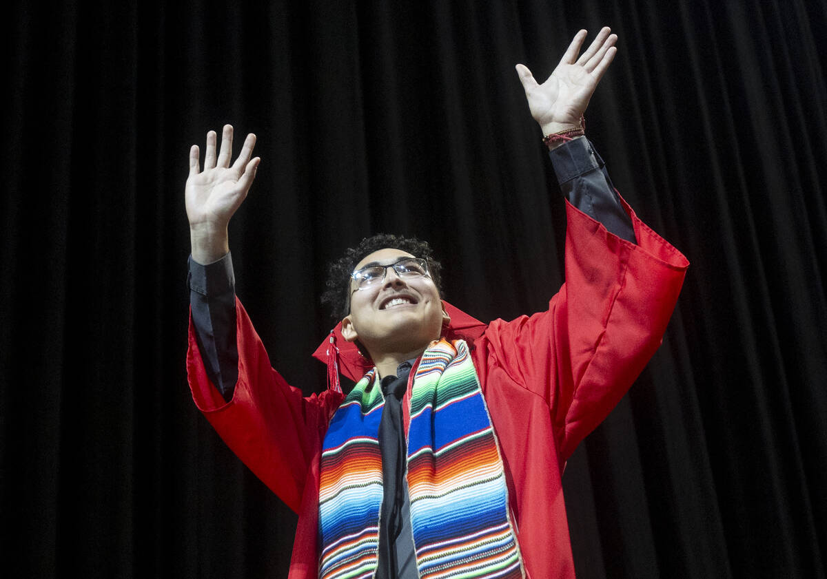 A graduate waves to the crowd while walking the stage during the UNLV winter commencement at th ...