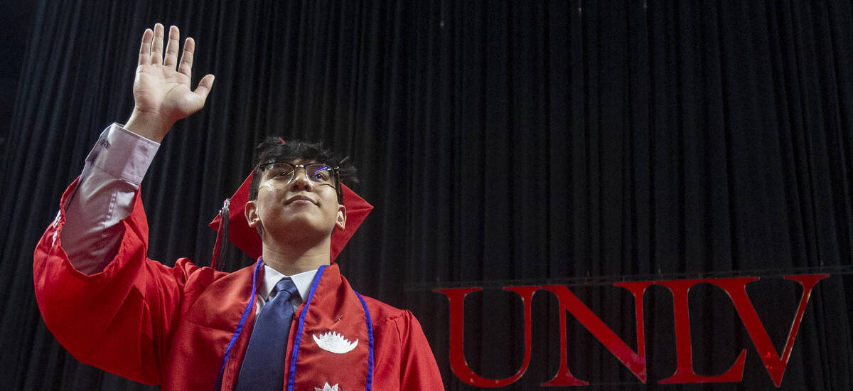 A graduate waves to the crowd after walking the stage during the UNLV winter commencement at th ...