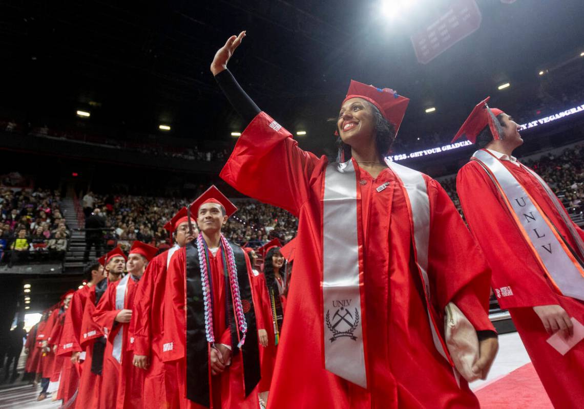 A graduate waves to the crowd while walking onto the floor during the UNLV winter commencement ...