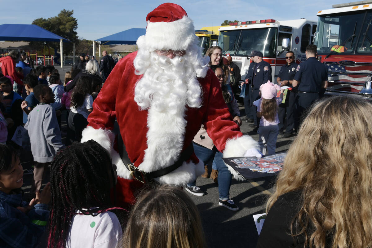 Santa Claus assists local firefighters as they deliver toys to children at Beckley Elementary S ...