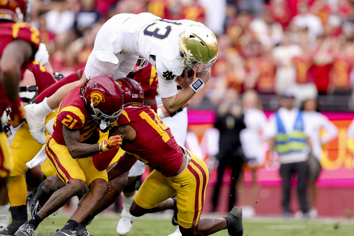 Notre Dame quarterback Riley Leonard, top, dives over Southern California cornerback Greedy Van ...