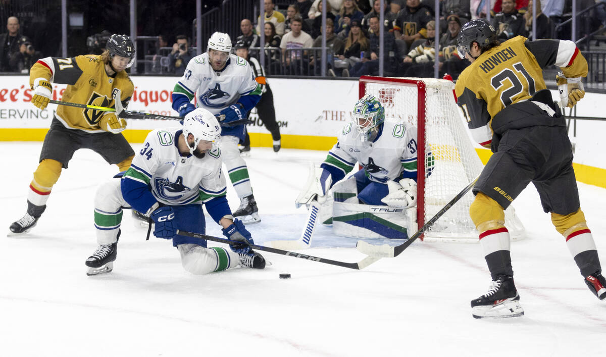 The Golden Knights and Vancouver Canucks compete for the puck during the first period of the NH ...