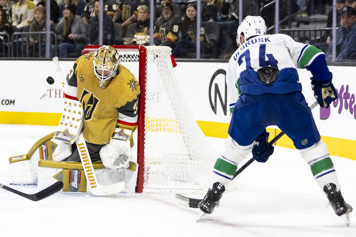 Golden Knights goaltender Adin Hill (33) blocks a shot by Vancouver Canucks left wing Jake DeBr ...