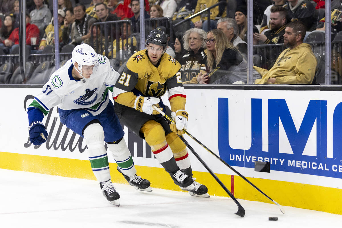 Golden Knights center Brett Howden (21) keeps the puck from Vancouver Canucks defenseman Tyler ...