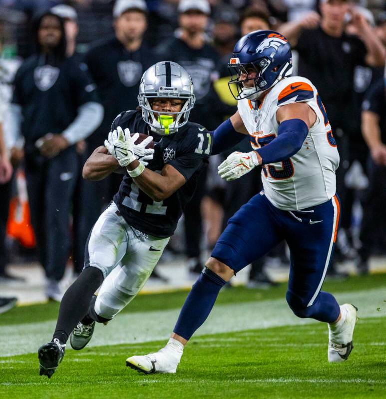 Raiders wide receiver Tre Tucker (11) secures a pass as Denver Broncos linebacker Cody Barton ( ...