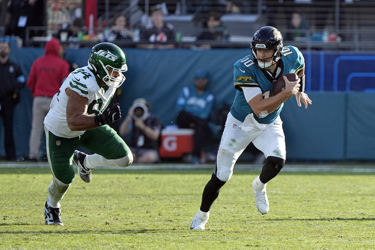 Jacksonville Jaguars quarterback Mac Jones (10) scrambles past New York Jets defensive end Solo ...