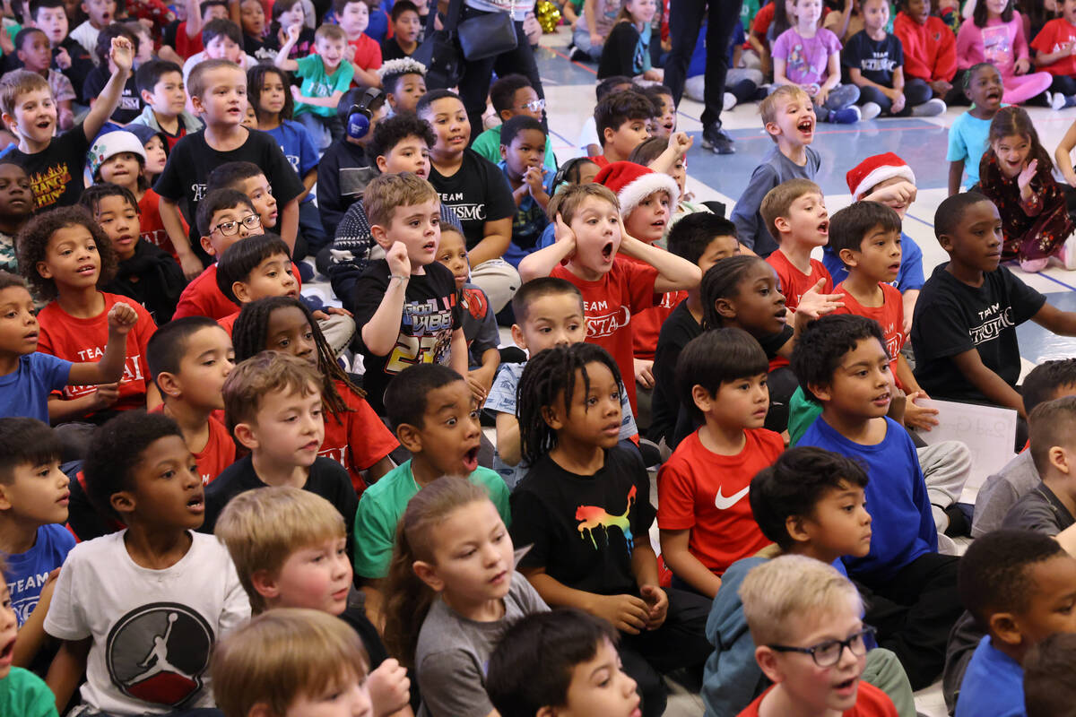 Students react to a mountain of toys on stage during a holiday party at Sewell Elementary Schoo ...