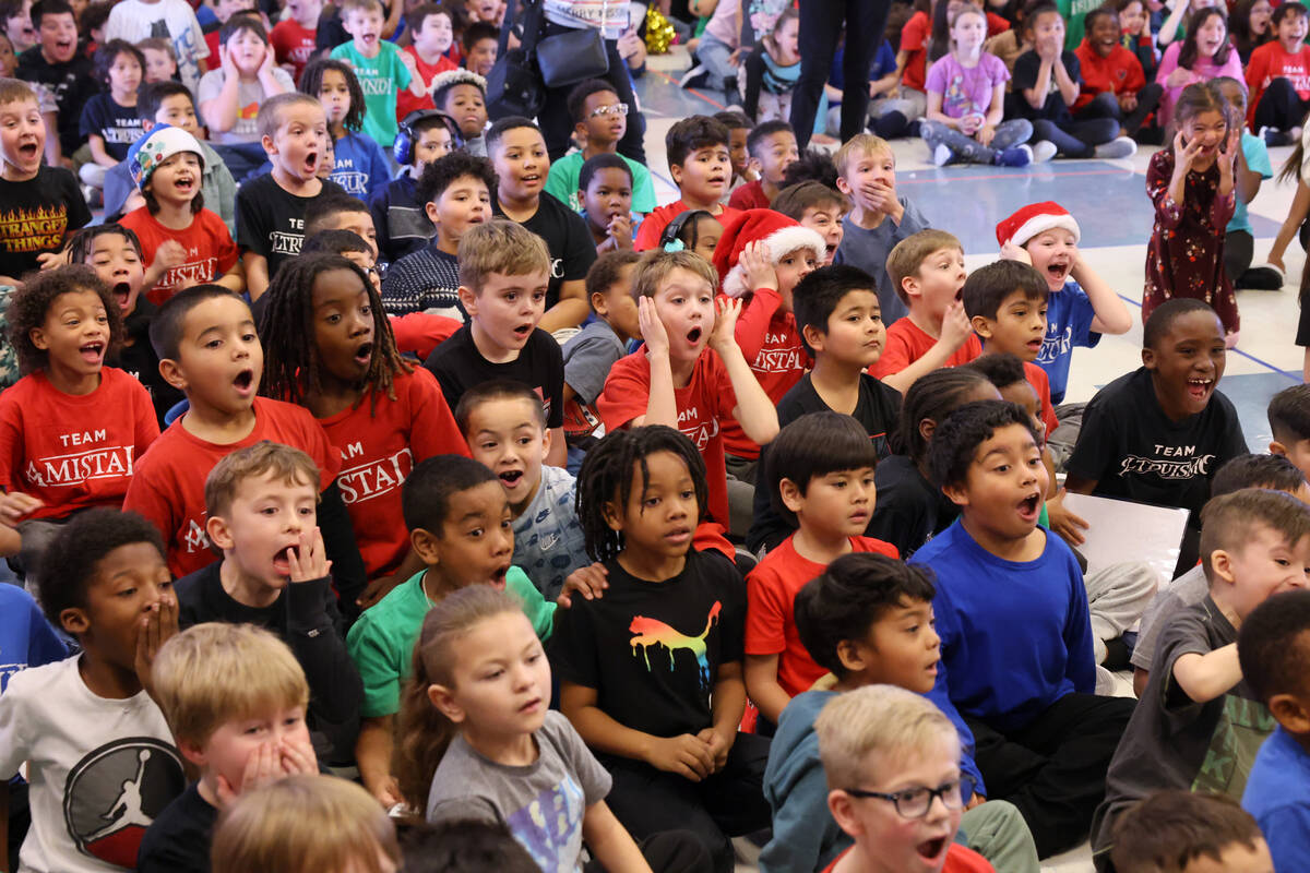 Students react to a mountain of toys on stage during a holiday party at Sewell Elementary Schoo ...