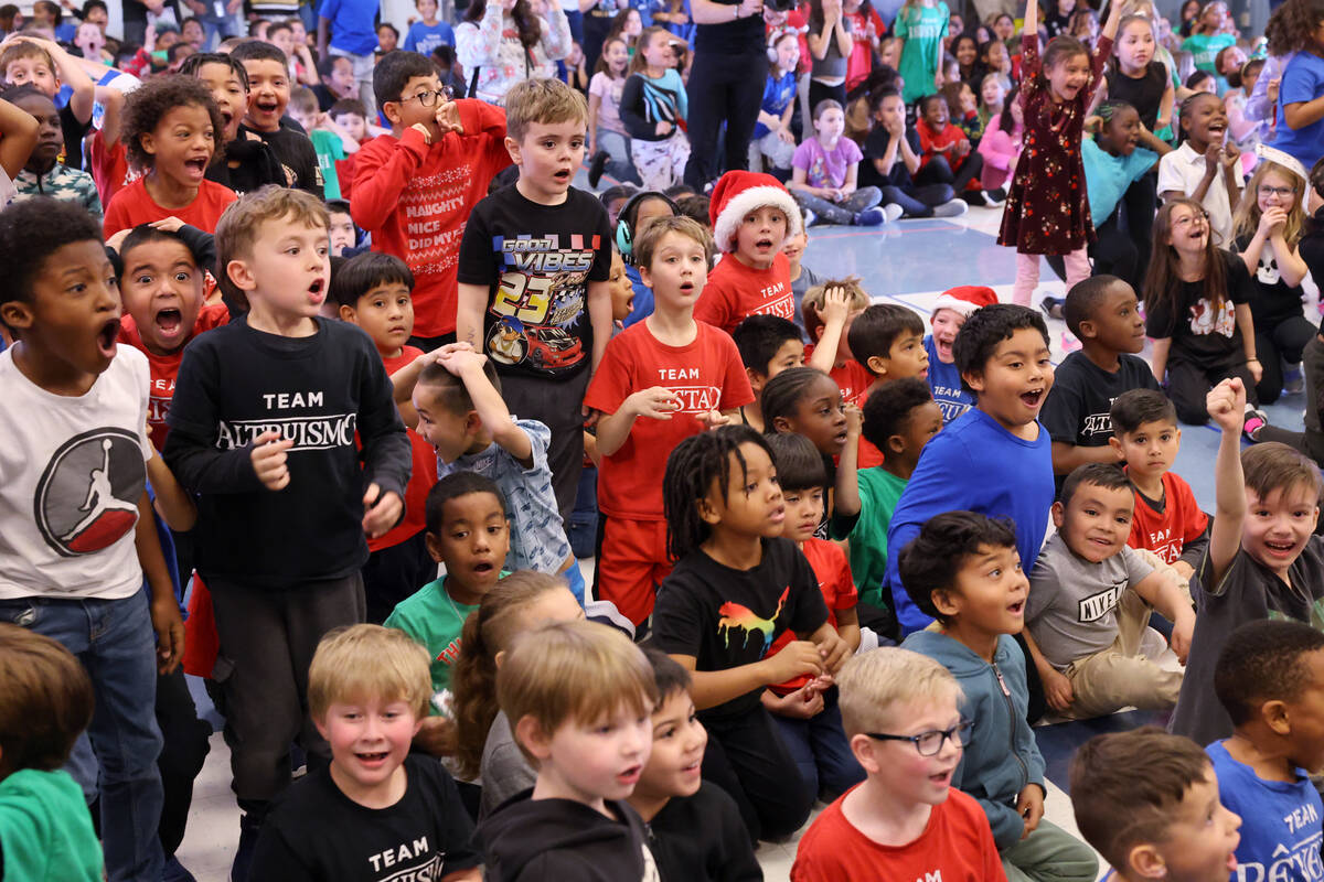 Students react to a mountain of toys on stage during a holiday party at Sewell Elementary Schoo ...