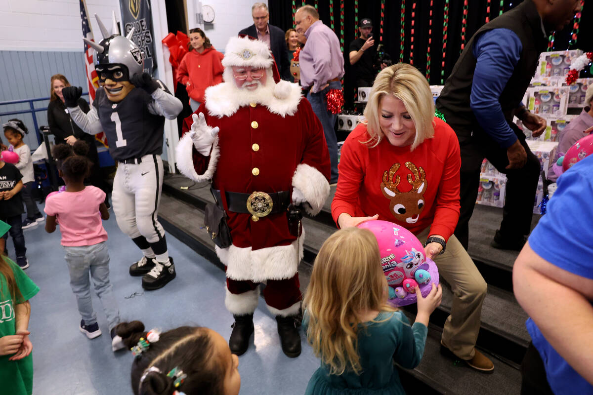 Sewell alumnus Henderson Mayor Michelle Romero hands out toys during a holiday party at Sewell ...