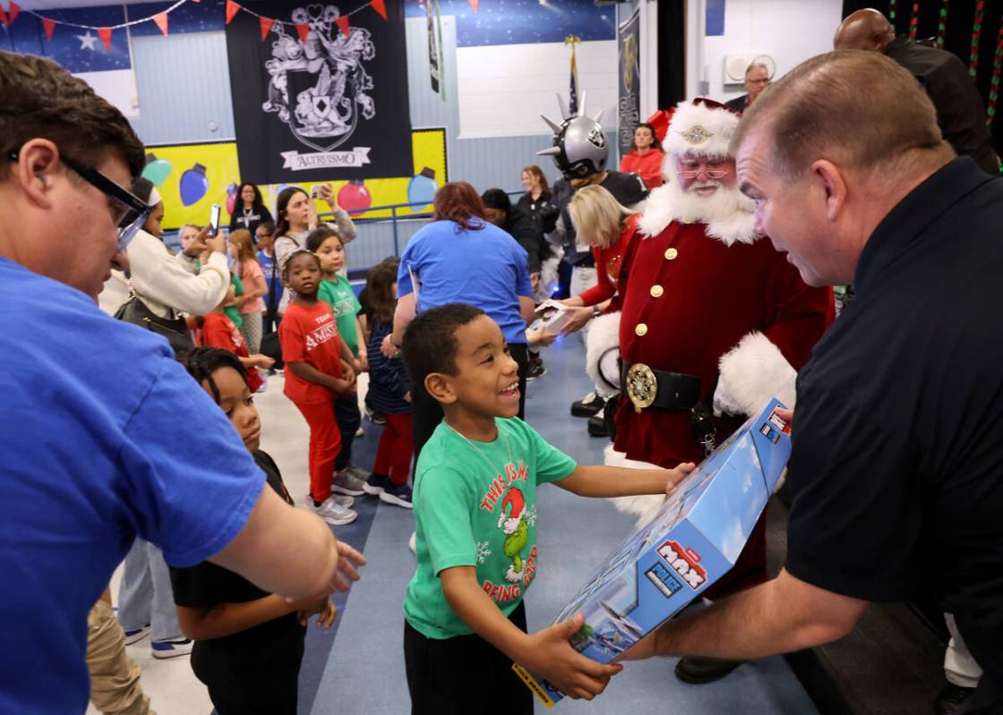 Jerry Dudley Jr. receives a toy from Henderson City Councilman Jim Seebock during a holiday par ...