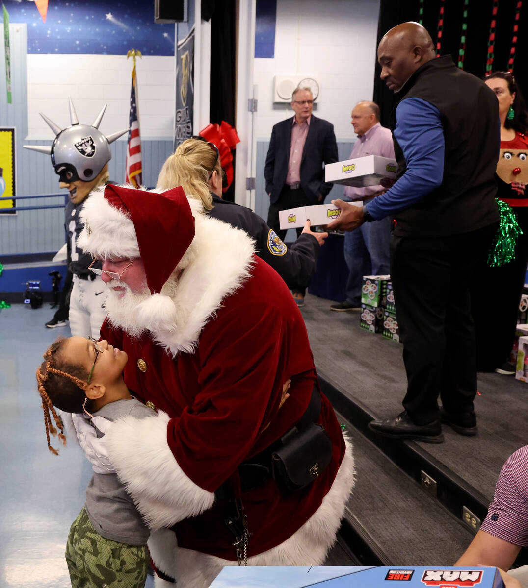 Apostolos Hiropoulos hugs Santa during a holiday party at Sewell Elementary School in Henderson ...