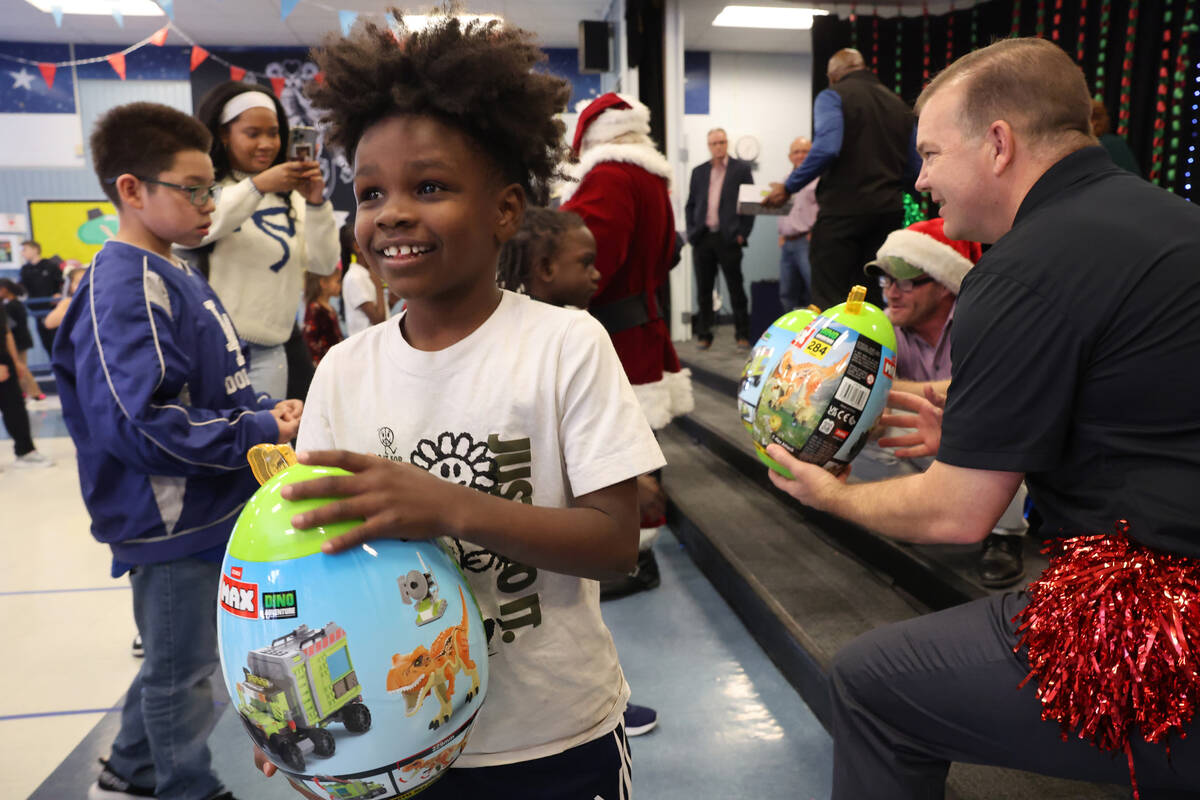 Elias Allen receives a toy during a holiday party at Sewell Elementary School in Henderson Frid ...