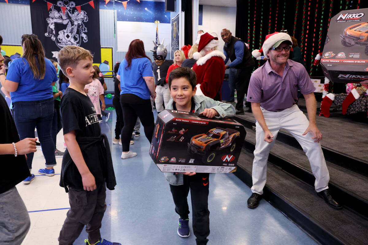 Alek Serrano receives a toy during a holiday party at Sewell Elementary School in Henderson Fri ...